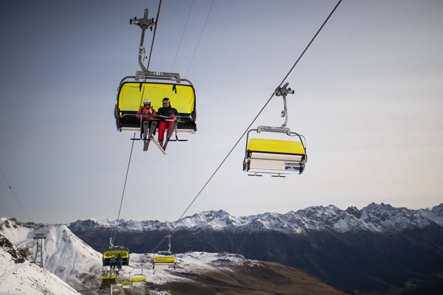 Menschen auf einem Sessellift, aufgenommen zum Start der Skisaison, am Sonntag, 25. Oktober 2020, auf Parsenn in Davos. Das Skigebiet Davos Klosters startet den Wochenendbetrieb. (KEYSTONE/Gian Ehrenz ...