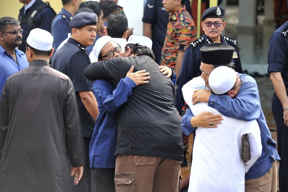 Unidentified Muslim hug each other outside an Islamic religious school following a fire on the outskirts of Kuala Lumpur Thursday, Sept. 14, 2017. The official said the fire, which killed people, most ...