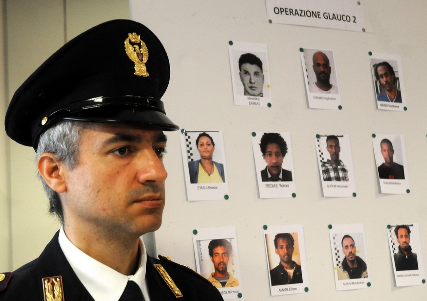 Ein italienischer Polizist vor einer Wand mit mutmasslichen Schleppern.