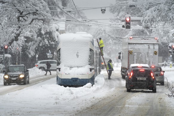 Mitarbeiter der Verkehrsbetriebe Zuerich VBZ versuchen ein im Schnee liegendes Tram zu reparieren, in Zuerich am Freitag, 15. Januar 2021. Nach den anhaltenden Schneefaellen in der oestlichen Schweiz  ...