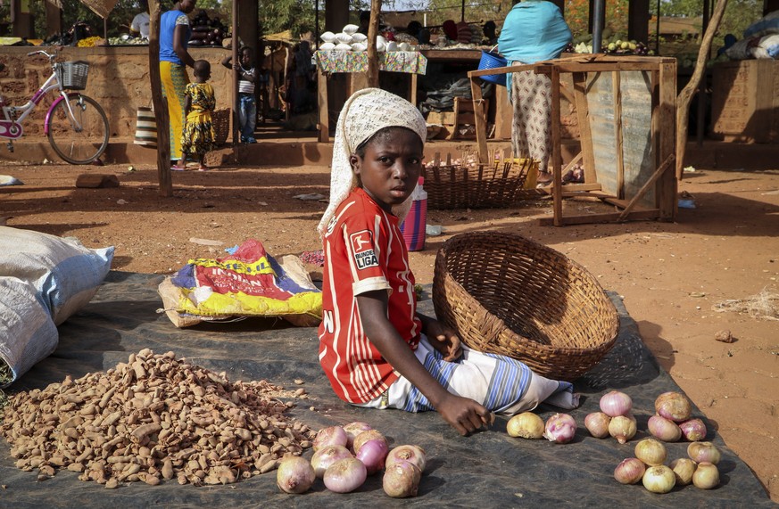 In this Wednesday, May 13, 2020, photo, a child sits on the ground selling onions at a market stall in Tougan, Burkina Faso. Violence linked to Islamic extremists has spread to Burkina Faso&#039;s bre ...
