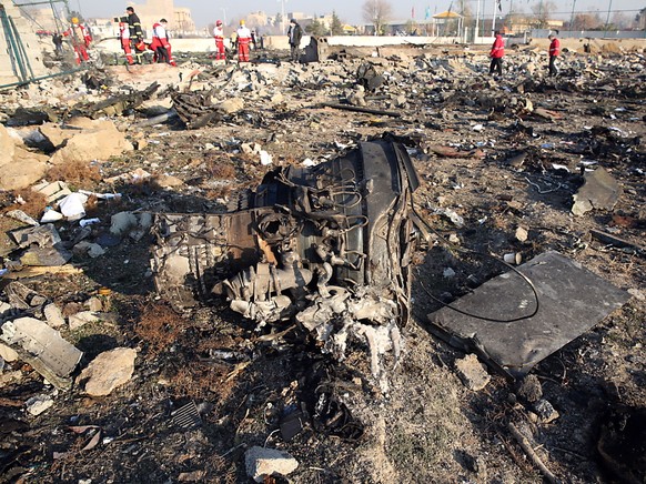 Einer der Flugzeugmotoren der abgestürzten Boeing 737 der Fluggesellschaft UIA liegt zwischen den Trümmern in der Nähe der iranischen Hauptstadt Teheran. Im Hintergrund arbeiten Ermittler an der Aufkl ...