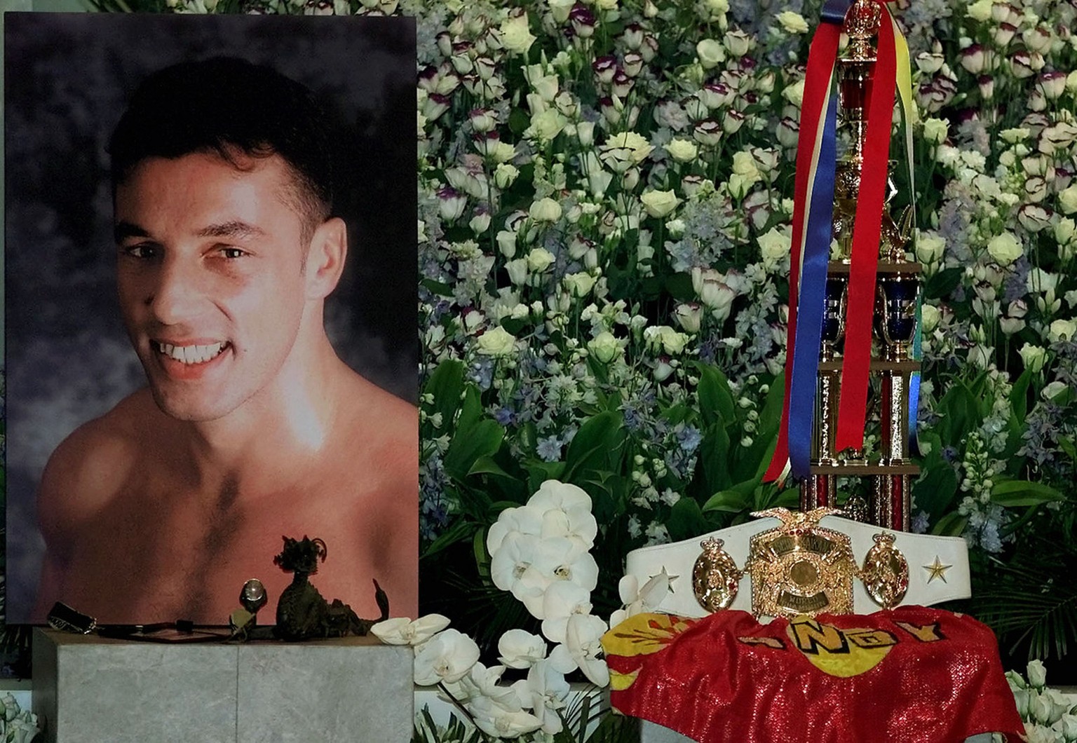 Swiss world kickboxing champion Andy Hug smiles in a picture next to his 1996 K-1 grad prix trophy on the altar during his wake at a Tokyo Buddhist temple Saturday, August 26, 2000. Hug died from an a ...