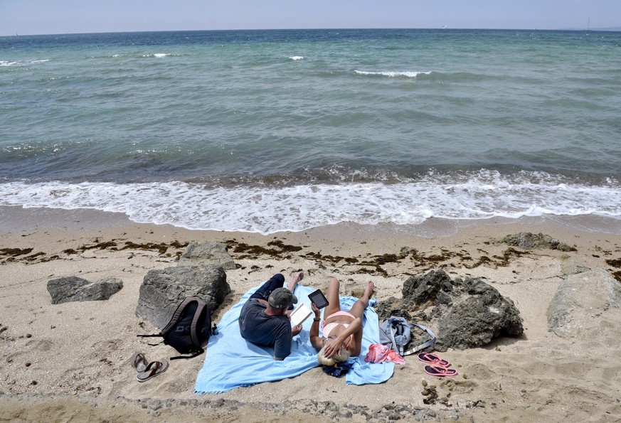 epa06755663 Two tourists rest on El Molinar beach, in Palma de Mallorca, Majorca Island, Spain, 22 May 2018. Authorities found several specimens of Portuguese man o&#039; war hydrozoan (Physalia physa ...