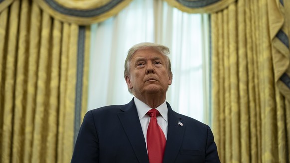 President Donald Trump listens during a ceremony to present the Presidential Medal of Freedom to former football coach Lou Holtz, in the Oval Office of the White House, Thursday, Dec. 3, 2020, in Wash ...