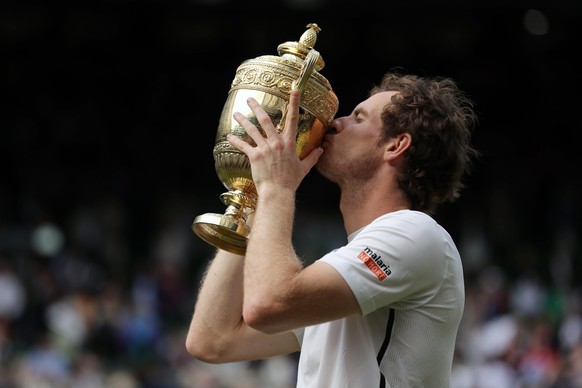 epa05418839 Andy Murray of Britain kisses the championship trophy following his win over Milos Raonic of Canada in the men&#039;s singles final of the Wimbledon Championships at the All England Lawn T ...