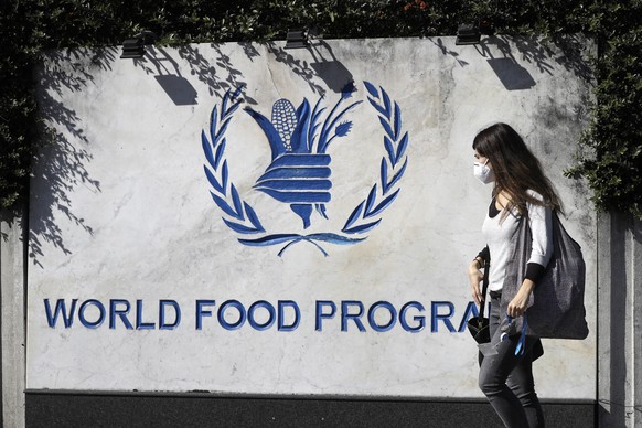 A woman walks past a sign at the entrance of the United Nations World Food Program (WFP), in Rome, Friday, Oct. 9, 2020. The WFP has won the 2020 Nobel Peace Prize for its efforts to combat hunger and ...