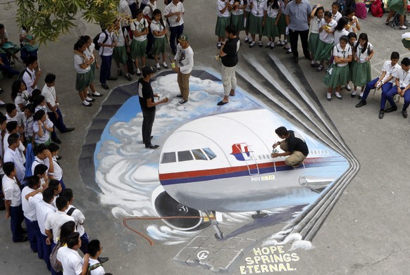 epa04129562 Filipino artists from the Guhit Visual Arts Group paint the image of Malaysia Airlines Flight MH370 at the Benigno Ninoy Aquino High School grounds in Makati City, south of Manila, Philipp ...