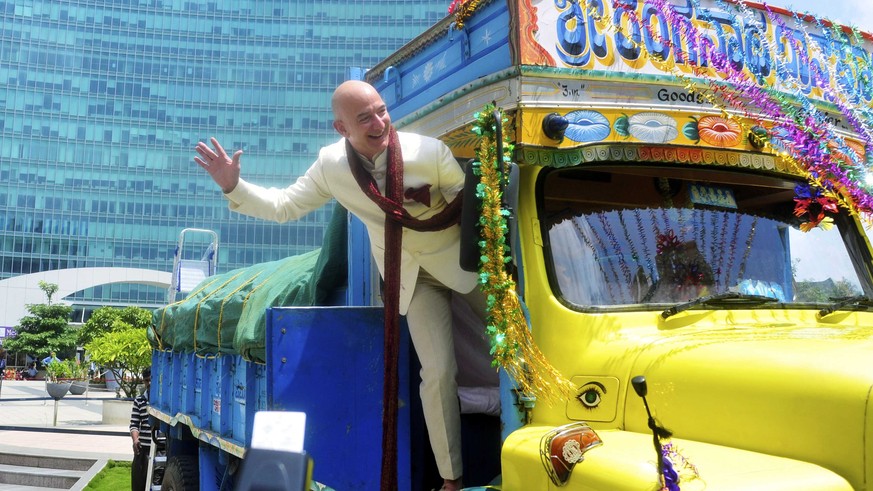 Jeff Bezos, founder and CEO of Amazon, poses as he stands on a supply truck during a photo opportunity at the premises of a shopping mall in the southern Indian city of Bangalore September 28, 2014. R ...