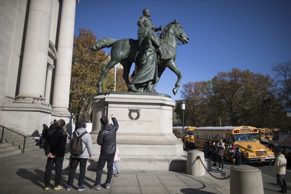 In this Nov. 17, 2017 file photo, visitors to the American Museum of Natural History in New York look at a statue of Theodore Roosevelt, flanked by a Native American man and African American man. The  ...