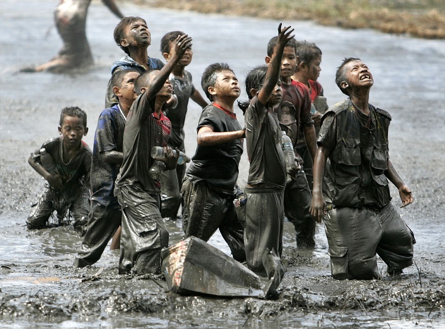 Refugee children try to catch relief goods tossed from an Australian military helicopter Monday, January 17, 2005 in a rice paddy in Lampaya, outskirts of Banda Aceh, Indonesia. Aceh was hardest-hit b ...