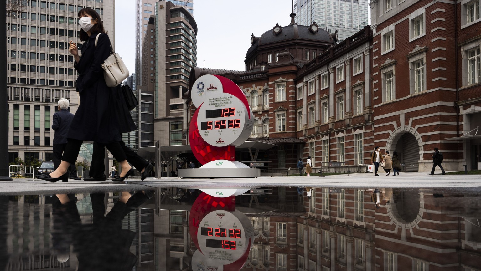 A countdown clock for the Tokyo 2020 Olympics is reflected in a puddle of water outside Tokyo Station in Tokyo, Monday, March 23, 2020. The IOC will take up to four weeks to consider postponing the To ...