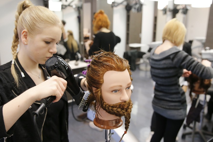 Madlen Huber, Coiffeur Lernende im 1. Lehrjahr, foehnt das Haar an einem Modell-Kopf mit Echthaar, am Dienstag, 31. Maerz 2015 in Bern. (KEYSTONE/Peter Klaunzer)