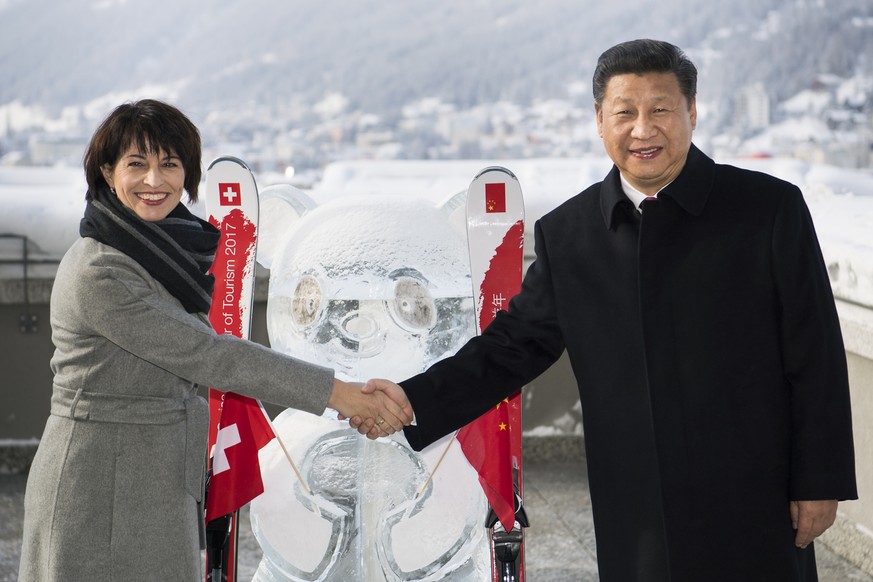 Swiss Federal President Doris Leuthard, left, shakes hands with China&#039;s President Xi Jinping, right, as they launch of the Swiss-Sino year of tourism next to a panda ice sculpture on the side lin ...