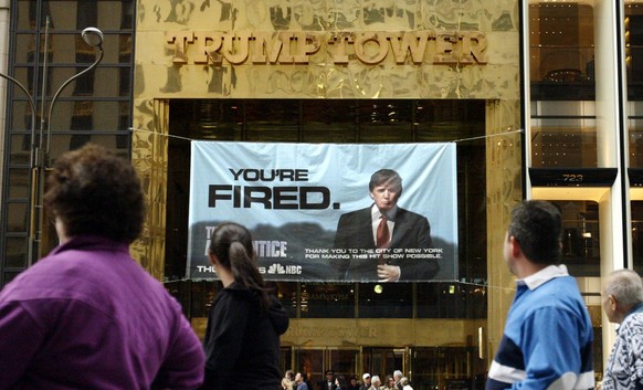 In this March 27, 2004 photo, passersby look at a sign from Donald Trump&#039;s television show, &quot;The Apprentice,&quot; hung on the Trump Tower in New York. The skyline shimmers, the music pulses ...