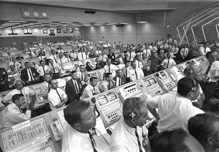 This July 1969 photo provided by NASA shows launch controllers in the firing room at the Kennedy Space Center in Florida during the Apollo 11 mission to the moon. In the third row from foreground at c ...