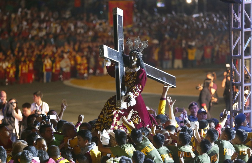 Roman Catholic devotees mount the image of the Black Nazarene on a hearse prior to a raucous procession to celebrate its feast day Tuesday, Jan. 9, 2018, in Manila, Philippines. A massive crowd of mos ...
