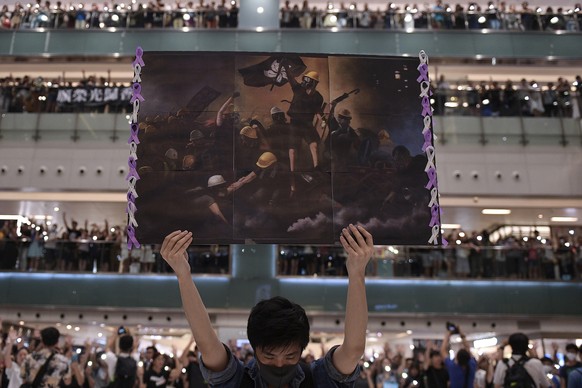 CATEGORY WINNER WORLD PRESS PHOTO 2020 - GENERAL NEWS STORIES - A man holds a poster as others gather at a shopping mall in the Shatin area of Hong Kong on September 11, 2019, to sing a recently penne ...