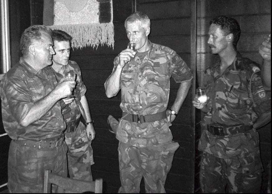 FILE - In this July 12, 1995 file photo Bosnian Serb army General Ratko Mladic, left, drinks with Dutch military Col. Thom Karremans, second right, in the Bosnian village of Potocari. A Dutch high cou ...