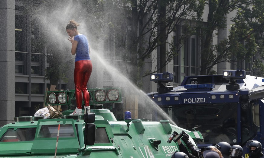 A woman is pepper-sprayed by police after she climbed an armored police vehicle on the first day of the G-20 summit in Hamburg, northern Germany, Friday, July 7, 2017. The leaders of the group of 20 m ...