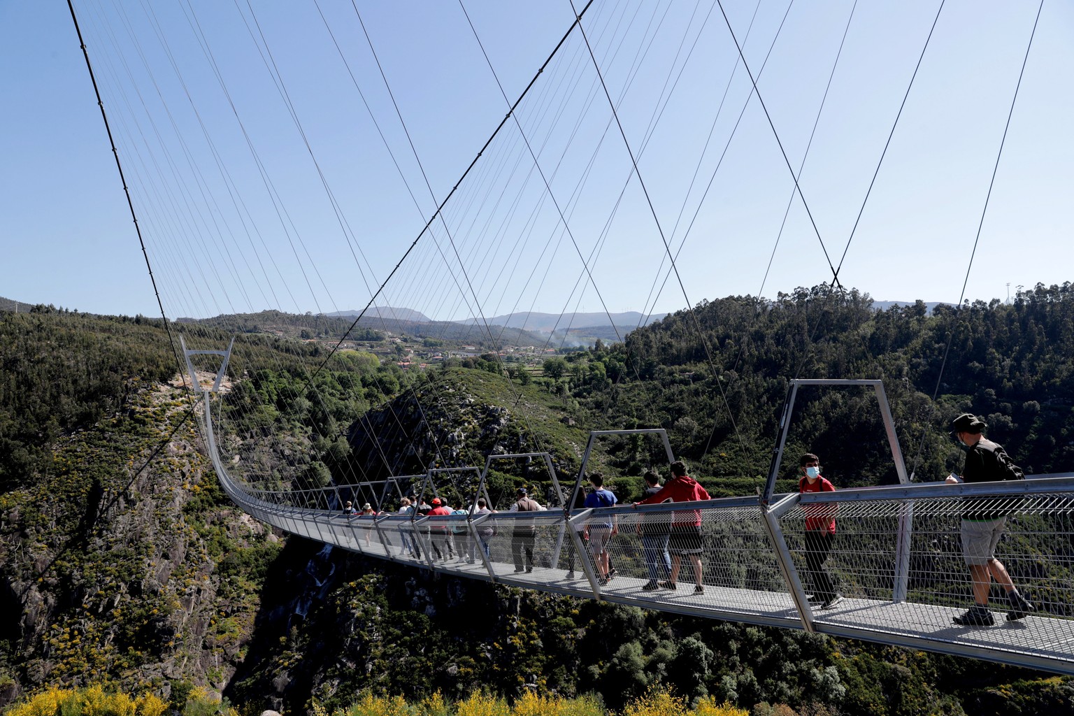 epa09164743 People walk across &#039;516 Arouca&#039;, considered the largest pedestrian suspension bridge in the world, at 516 meters long and 175 meters high, in Arouca, Portugal, 16 April 2021 (iss ...