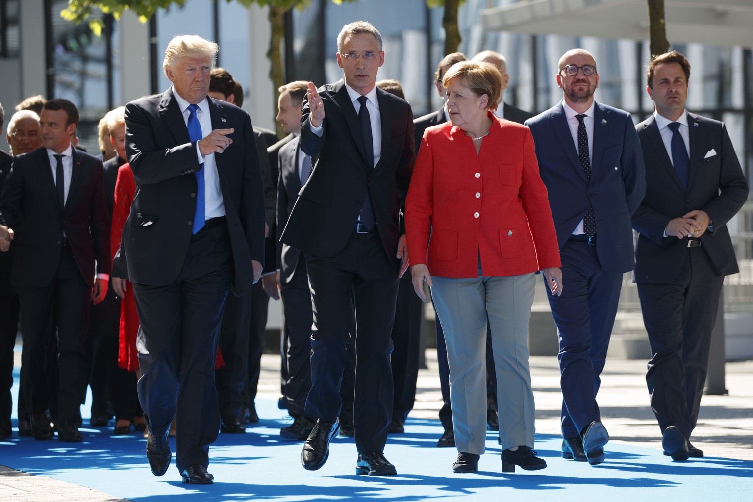 NATO Secretary General Jens Stoltenberg, center, walks with President Donald Trump and German Chancellor Angela Merkel during a ceremony to unveil artifacts from the World Trade Center and Berlin Wall ...
