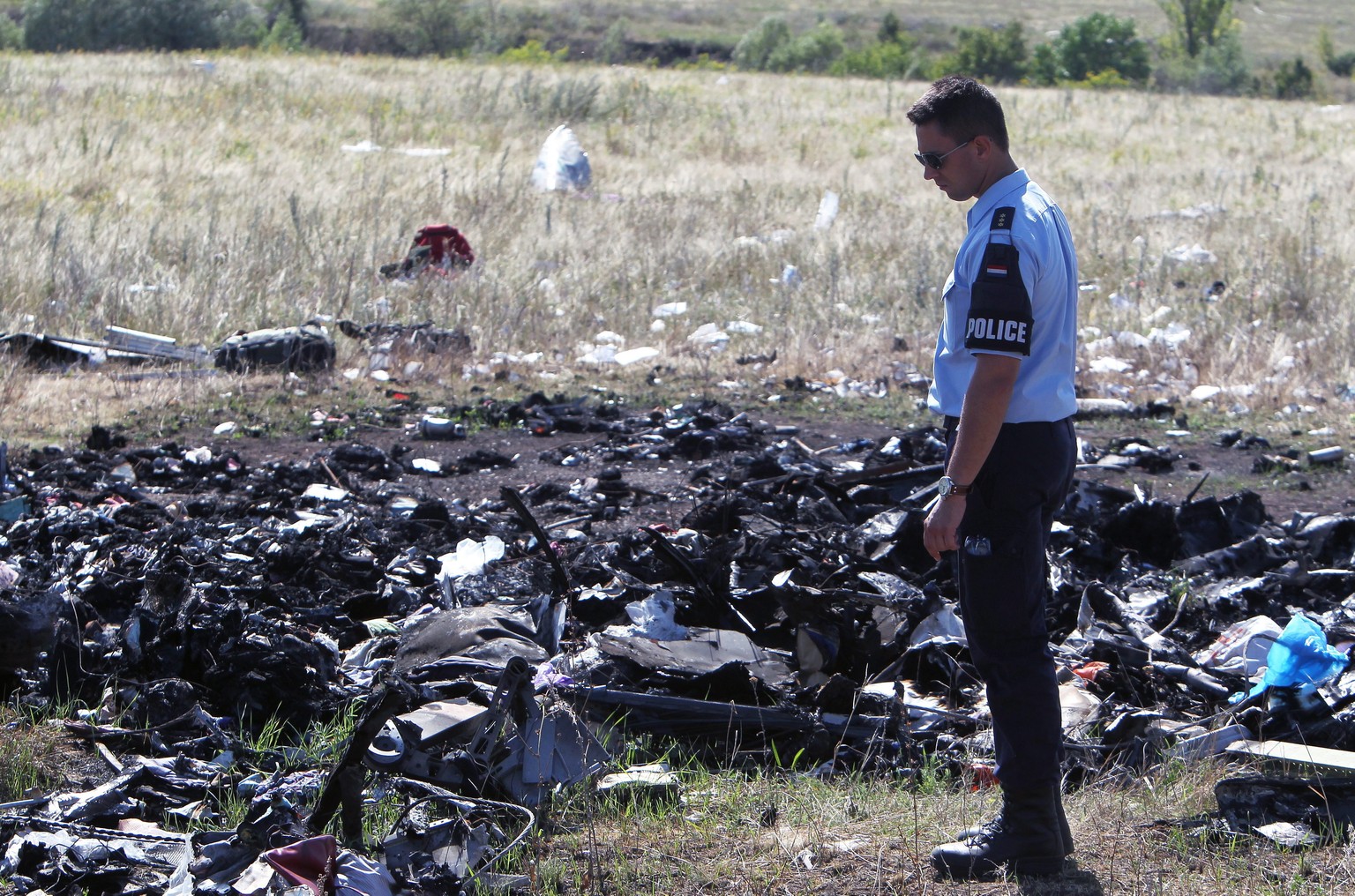 Ein Polizist vor den Trümmern des abgestürzten MH17 am 17. Juli. Die Ermittlungen sind noch immer im Gange – trotz schwerster Bedingungen.