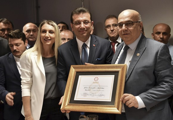 Ekrem Imamoglu, the candidate of Turkey&#039;s main opposition Republican People&#039;s Party, center, and his wife Dilek Imamoglu pose with a certificate confirming his election victory, in Istanbul, ...