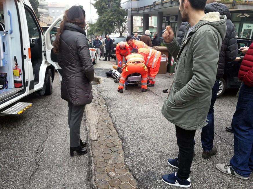 epa06493400 Paramedics treat an injured person that was shot from a passing vehicle in Macerata, Italy, 03 February 2018. According to the local authorities, the town at the eastern Italian coast near ...