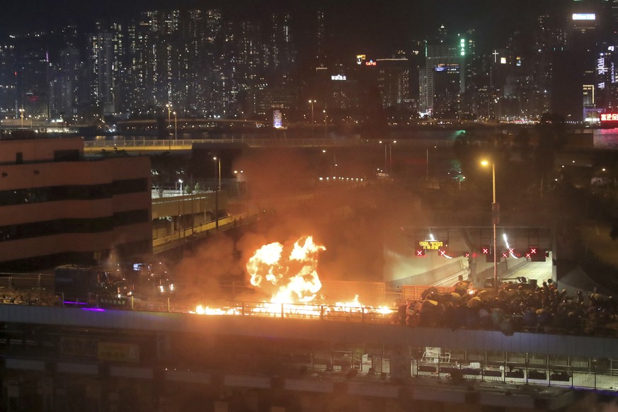 Protestors hurl molotov cocktails as armored police vehicles approach their barricades on a bridge over a highway leading to the Cross Harbour Tunnel in Hong Kong, Sunday, Nov. 17, 2019. A Hong Kong p ...