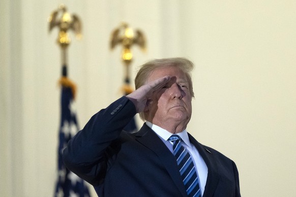President Donald Trump salutes on the Blue Room Balcony upon returning to the White House Monday, Oct. 5, 2020, in Washington, after leaving Walter Reed National Military Medical Center, in Bethesda,  ...