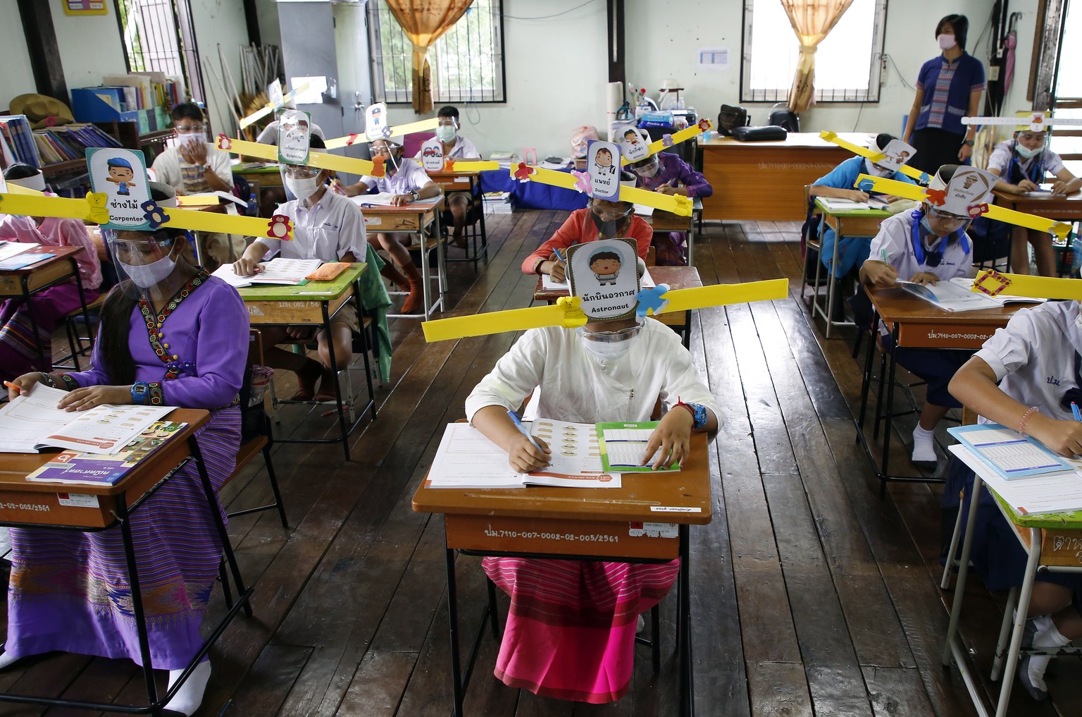 epa08524440 Students wearing face masks and one-meter social distancing wing-hats take part in a class at Ban Pa Muad School in San Sai district, Chiang Mai province, Thailand, 03 July 2020. Ban Pa Mu ...