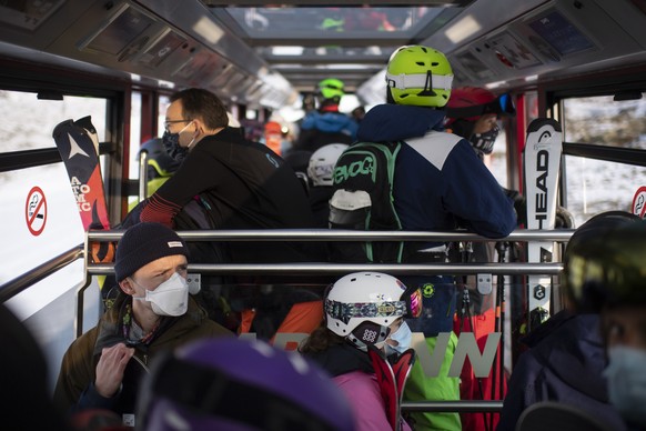 Menschen mit Schutzmasken in der Parsenn-Bahn, aufgenommen zum Start der Skisaison, am Sonntag, 25. Oktober 2020, in Davos. Das Skigebiet Davos Klosters startet den Wochenendbetrieb. (KEYSTONE/Gian Eh ...