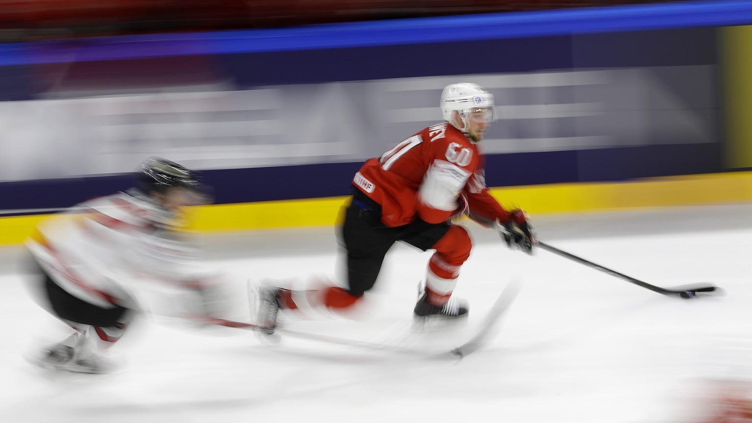 In this photo shot with a slow shutter speed Switzerland&#039;s Tristan Scherwey, right, chases the puck during the Ice Hockey World Championships semifinal match between Canada and Switzerland at the ...