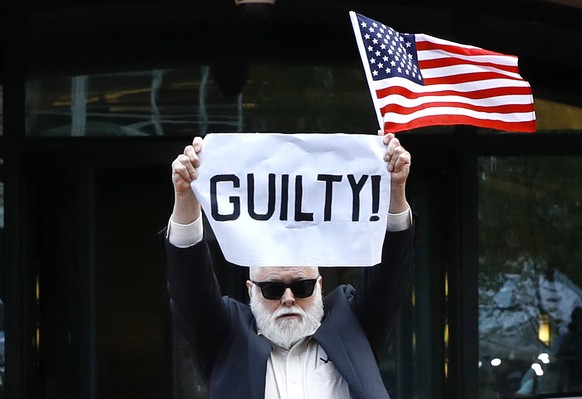 Protester Bill Christeson holds up a sign saying &quot;guilty&quot; as the first count of guilty comes in at he trial of former Donald Trump campaign chairman Paul Manafort, at federal court in Alexan ...
