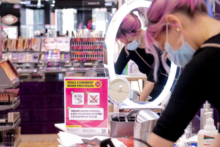 epa08409491 A worker wearing a protective face mask cleans make-up products in the Swiss department store Manor during the preparation for the reopening by respecting the sanitary rules during the sta ...