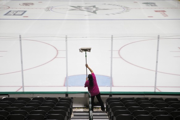 A worker cleans the safety glass at American Airlines Arena, home of the Dallas Stars NHL hockey club, Thursday, March 12, 2020 in Dallas. The NHL announced Thursday it is suspending its season indefi ...