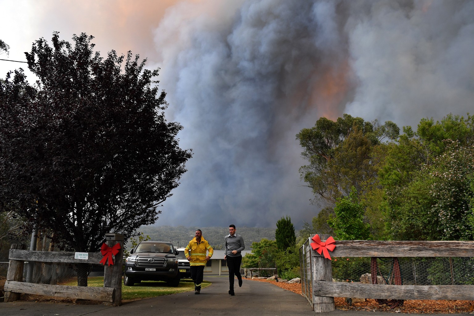 epa08080902 A New South Wales (NSW) Rural Fire Service (RFS) officer and a resident run from a bushfire burning along the Old Hume Highway near the town of Tahmoor, NSW, Australia, 19 December 2019. S ...