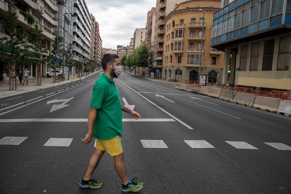 epa08542118 A man with a protective face mask crosses the empty streets of Lleida, Catalonia, Spain, 12 July 2020. Catalonian regional government has decretated that Lleida and another seven villages  ...