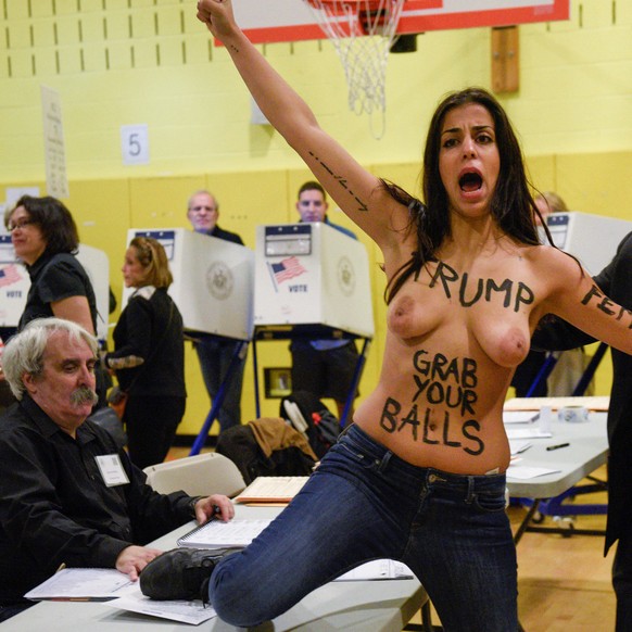 A topless protester shouting slogans is escorted out of the basement of the P.S. 59 polling station, the location where Republican presidential candidate Donald Trump was scheduled to cast his ballot  ...