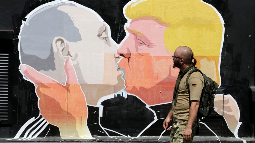 A man walks past a graffiti depicting U.S. Republican presidential Donald Trump (R) and Russia&#039;s President Vladimir Putin in Vilnius, Lithuania, June 1, 2016. REUTERS/Ints Kalnins FOR EDITORIAL U ...