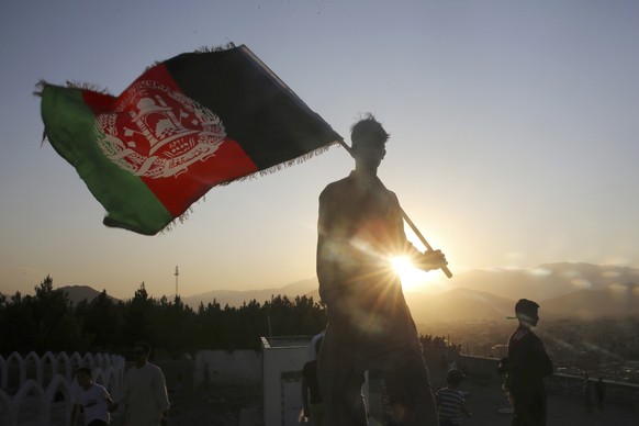 FILE - In this Aug. 19, 2019, file photo, a man waves an Afghan national flag during Independence Day celebrations in Kabul, Afghanistan. Washington