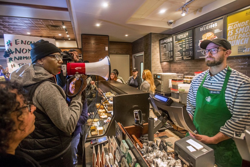 FILE – In this April 15, 2018, file photo, Asa Khalif, left, a Black Lives Matter activist from Philadelphia, demands the firing of a Starbucks cafe manager who called police, resulting in the arrest  ...