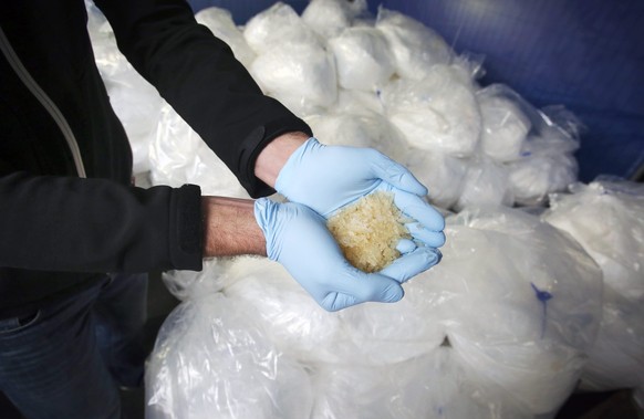 epa04487940 An investigator of the Federal Criminal Police Office (BKA) holds some of 2.9 tons of seized Crystal Meth on display for media in Wiesbaden, Germany, 13 November 2014. Investigators from s ...