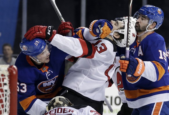 New York Islanders&#039; Casey Cizikas, left, and Cal Clutterbuck, right, scuffle with New Jersey Devils&#039; Nico Hischier, center, during the second period of an NHL hockey game, Sunday, Jan. 7, 20 ...