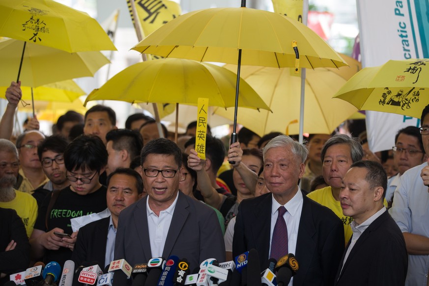 epa07524296 Occupy Central activists Chan Kin-man (L, front) Reverend Chu Yiu-ming (C, front) and Benny Tai (R, front) speak to the media before their sentencing, outside West Kowloon Magistrates Cour ...