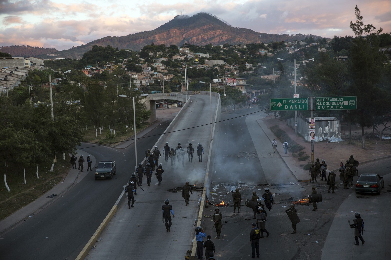 Police walk on a road where signs list the street names &quot;Paradise&quot; and &quot;The Valley of Angels&quot; after firing tear gas to remove protesting supporters of presidential candidate Salvad ...