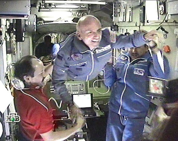 TV-grab taken from the Russian NTV channel shows Russian cosmonauts Talgat Musabayev (R) and Yuri Usachev (L) helping first-ever space tourist Dennis Tito (C) to enter the International Space Station  ...