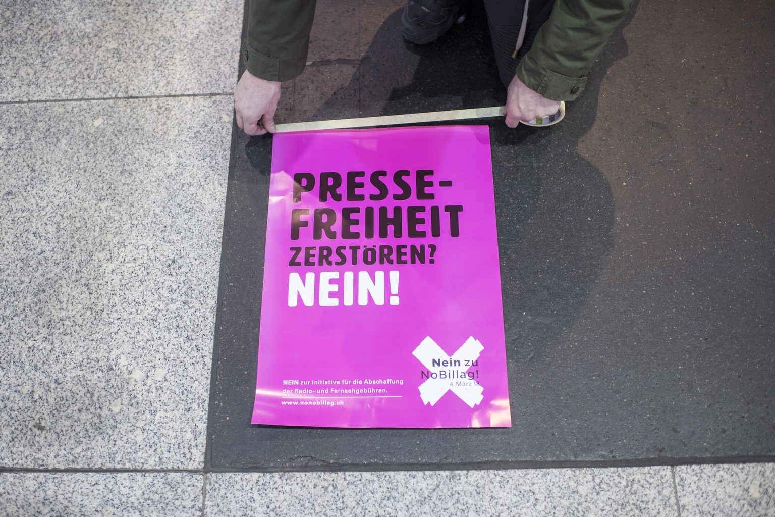 Ein Mann klebt Plakate mit der Aufschrift &quot;Pressefreiheit zerstoeren? Nein!&quot; im Hauptbahnhof in Zuerich unter der &quot;No Billag&quot;-Aktion &quot;Musik gegen den Sendeschluss&quot;, aufge ...