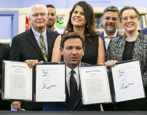 Florida Gov. Ron DeSantis, center, reacts after signing bills revamping Florida&#039;s literacy and early childhood learning in West Miami Middle School in Miami, Florida on Tuesday, May 4, 2021. (Mat ...